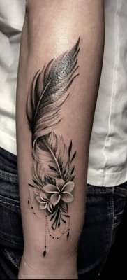 Tatouage plume enlacée avec deux fleurs